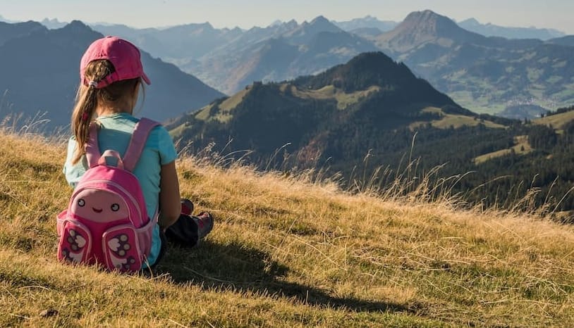 a child sits on a hiking trail in the southwest mountains