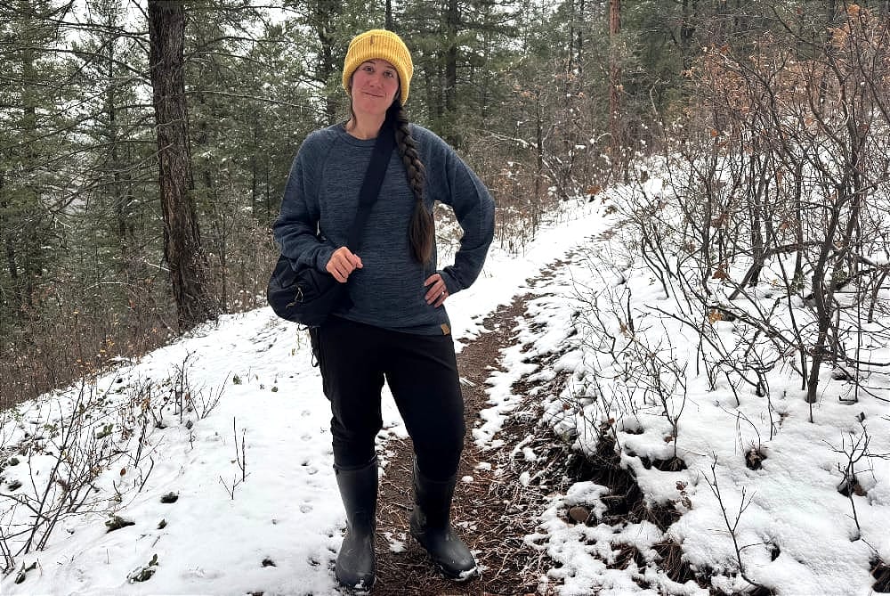 a woman hiking on a snowy forest trail wearing the patagonia nano-air light bottoms