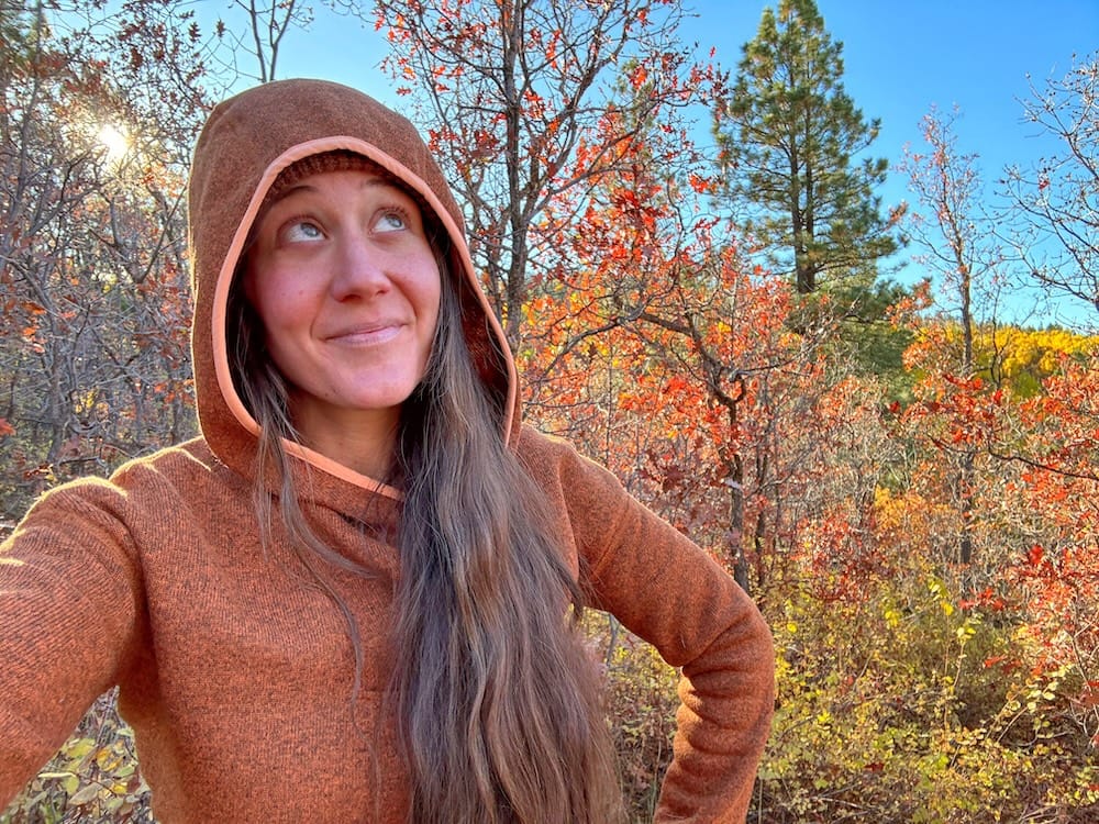 a woman wears the stio sweetwater fleece hoodie on a cold hike, which it's perfect for in 2025!