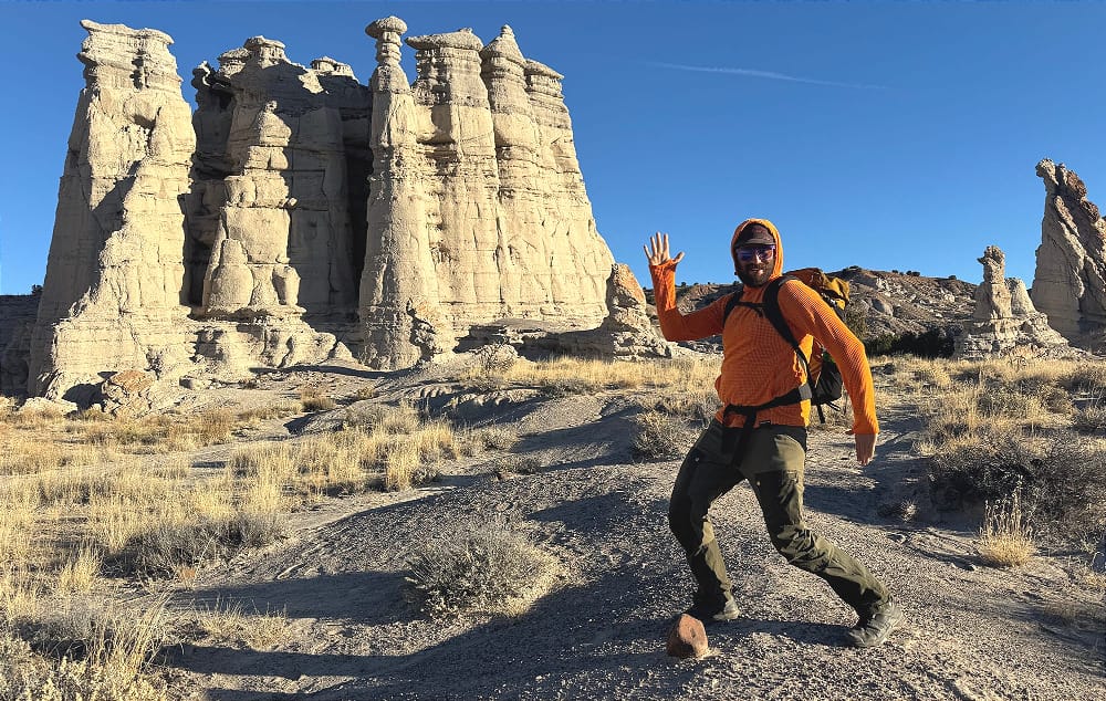 a man wears a best fleece hoodie on the market in 2025 in the high desert near badlands and strikes a pose