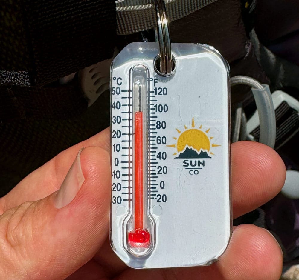 a hiker's thermometer displays a high over almost 100° on a hot day in the desert