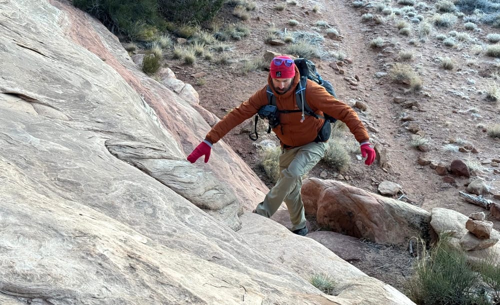 a hiker goes up slickrock on the Salt Flat and Big Spring Canyon Loop in Canyonlands National Park