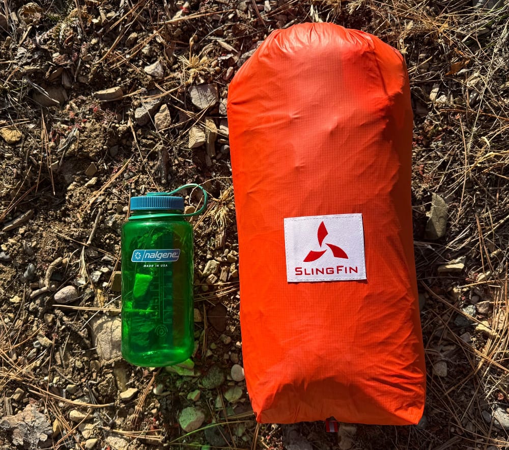 slingfin portal 3 tent all packed up in its stuff sack sitting next to a nalgene bottle for a size comparison