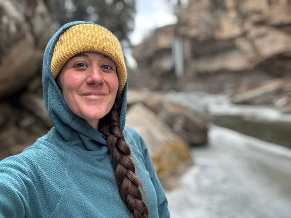 a woman wearing the turtle fur whitman beanie on a cold hike with a frozen waterfall