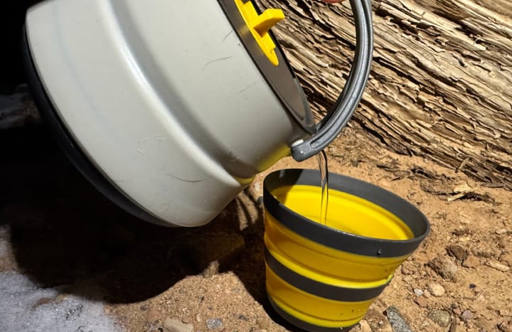 Frontier Ultralight Collapsible Kettle By Sea To Summit pouring water into a cup at a camp during a backpacking trip