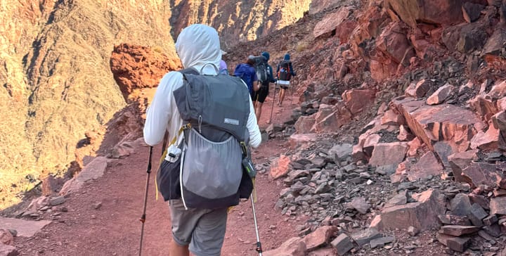 Scenic southwest trail with a hiker carrying an ultralight backpack, surrounded by canyon walls and steep slopes